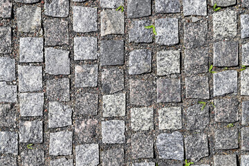 Texture of an old stoneblock pavement cobbled with square granite blocks as an old-fashioned architectural, background