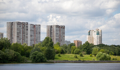 Multi-storey buildings in the green zone of the park against the sky.