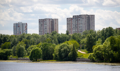 Fototapeta na wymiar Multi-storey buildings in the green zone of the park against the sky.