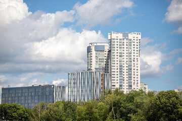 Obraz na płótnie Canvas Multi-storey buildings in the green zone of the park against the sky.
