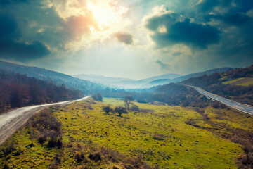 Fototapeta na wymiar Aerial view of the countryside, country road, and highway on the hills on a sunny spring day. Carpathian mountains, Ukraine