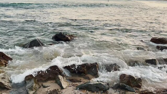 Holiday evening view sea waves washing onto rocky shore. Slow Motion and relaxing scene in background.