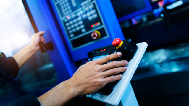Worker hand controling cnc machine at workshop