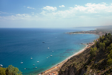 Fototapeta na wymiar Photograph of the coast of Taormina in Sicily, houses, boats and trees.