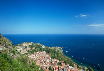 Naklejka na ściany i meble Photograph of the coast of Taormina in Sicily, houses, boats and trees.