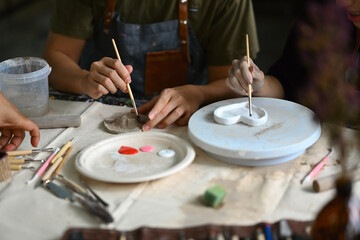 Obraz na płótnie Canvas Image of young asian man enjoying creative process, creating handmade ceramics in pottery workshop