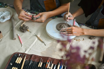 Obraz premium Craftspeople wearing aprons working with raw clay, shaping and decorating pottery in workshop