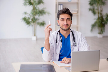 Young male doctor holding syringe at the hospital