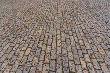 Cobblestones lined up in a street make up an old-fashioned background featuring lines