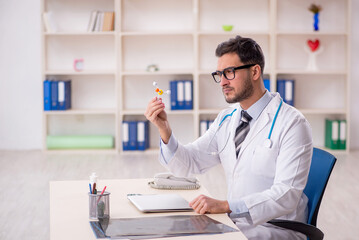 Young male doctor holding molecular model in the clinic