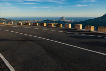 Naklejka premium Empty winding mountain road, Calpe village at background, Alicante, Costa Blanca, Spain