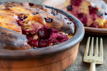 Sweet cottage cheese casserole with red cherry and semolina on wooden table. Ceramic bowl with...