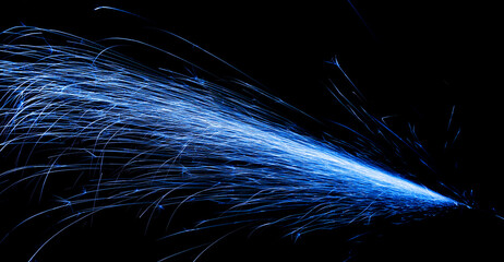 blue fast-flying sparks from angle grinders on black background
