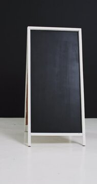 Vertical video of blackboard sign on white stand with copy space on black background