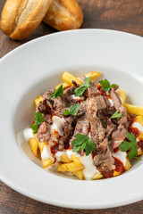 Turkish food Çökertme Kebab. Kebab made with thinly sliced beef steak on french fries and yoghurt