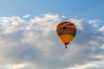 A multi-colored balloon flies against the background of a cloudy sky