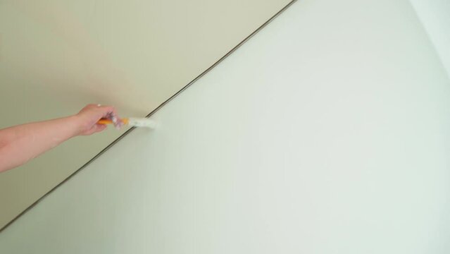 Painting a white wall with a brush during a cometic repair.