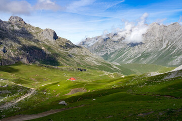 Aliva meadows with the royal chalet and its red roof standing out among the mountains of the national park of picos de europa, Cantabria, Spain.
