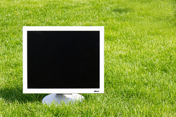 Old computer display on green grass