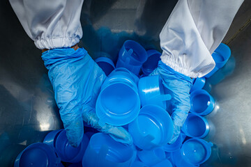 Worker holding Lots of the blue plastic bottle cap that Prepare for assembly.
