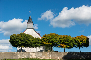 Fototapeta na wymiar Alte Kapelle in der Eifel mit Bäumen und blauem Himmel 
