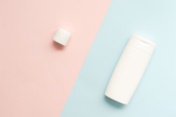 Flat lay of cosmetic bottles and tubes on two colored background