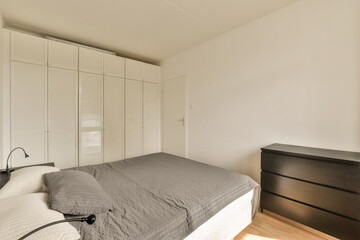 a bedroom with a bed, dresser and mirror on the wall in front of the room is white shutters