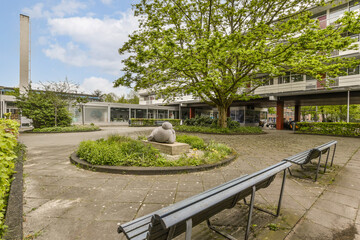 a bench in the middle of an outdoor area with trees and plants on either side of the benches are empty