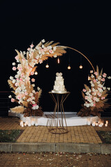 Beautiful wedding arch with flowers and a large wedding cake. High quality photo. High quality photo