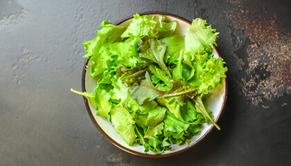 mix lettuce leaves salad in a plate (fresh green snack). food background. top