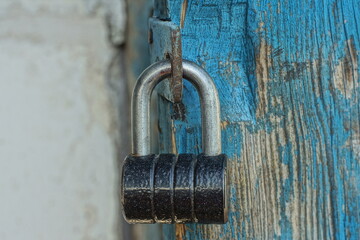 one new hinged modern closed safe industrial iron lock hanging on the iron bracket of old blue...