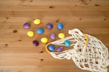 Easter eggs in a string bag on a wooden background, top view
