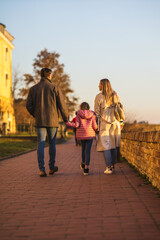 Obraz premium A happy three-member family walks and enjoys a beautiful winter day.