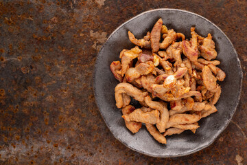 tasty fried pork fillet in wabi sabi plate on rusty texture background with copy space for text, top view, flat lay