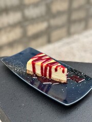 A Strawberry Cheesecake on an indigo blue ceramic plate with a dark-tone loft cafe background