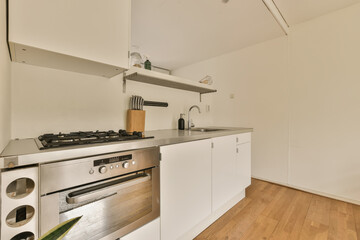 a kitchen area with an oven, stove and sink in the middle of the room there is a wooden floor