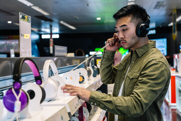 Focused ethnic man choosing headphones in store