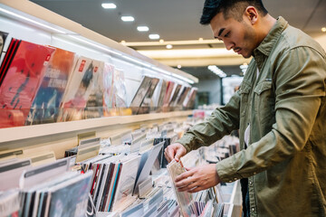 Asian man choosing vinyl record in store