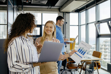 Obraz na płótnie Canvas Happy business colleagues using laptop discussing idea