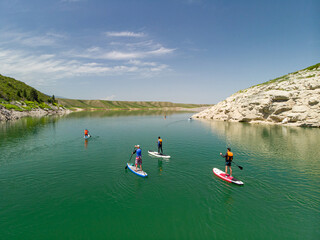 A group of tourists swims on SUP boards on a mountain lake