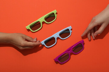 Sun-protective, colored glasses on a bright orange background