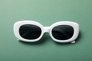 Sunglasses are black with a white frame, on a green background