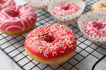 Glazed donuts on grid on marble background, close up