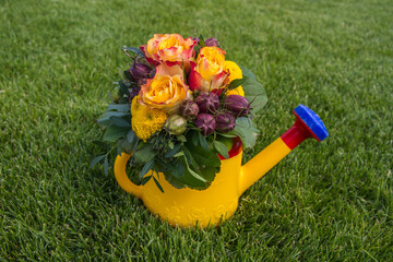 Cute bunch of flowers on grass with watering can