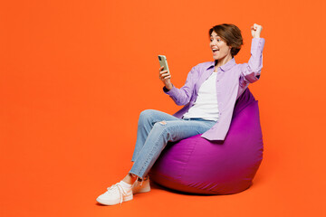 Full body young fun woman she wear purple shirt white t-shirt casual clothes sit in bag chair hold...