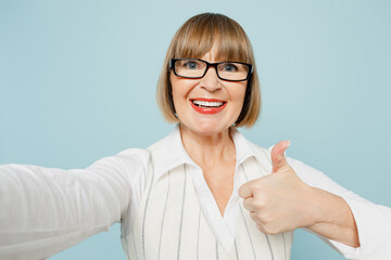 Close up fun employee business woman 50s wear white classic suit glasses formal clothes doing selfie shot pov on mobile cell phone isolated on plain pastel blue background Achievement career concept