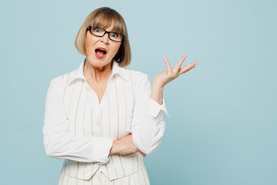 Blonde shocked questioned sad employee business woman 50s wear white classic suit glasses formal clothes look camera spread hand isolated on plain pastel blue background. Achievement career concept.