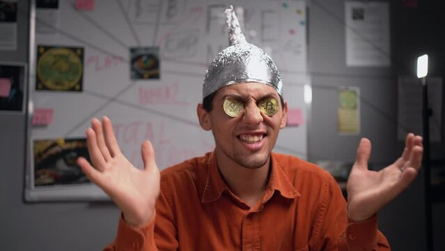 Conspiracy theorist in a protective foil hat with bitcoin coins in his eyes. Conspiracy theory concept. Cryptocurrency.