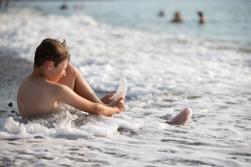 Fototapeta na wymiar A teenage boy is sitting on the seashore.