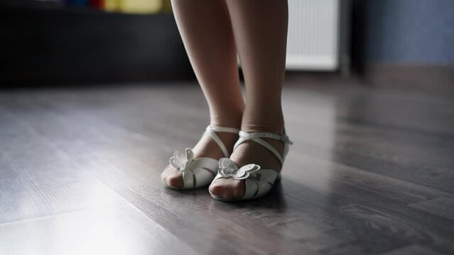 Close-up side view of child foots in dancing shoes on the floor in studio. Dance training class for kids. Girls athlete concept 